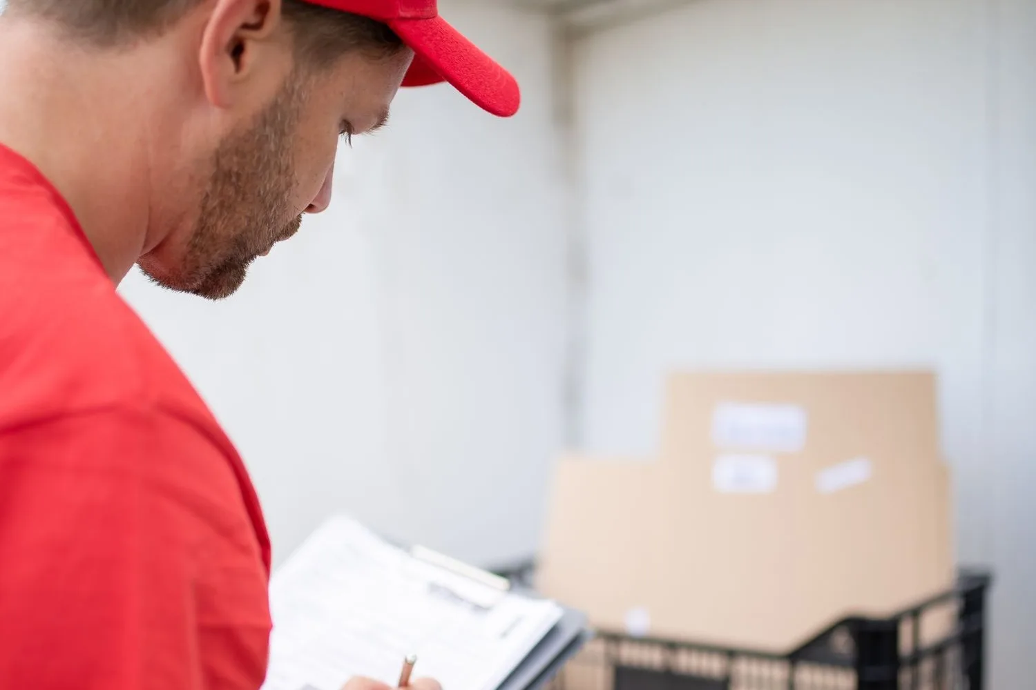 A driver filling in a paper delivery note by hand next to the boxes before dropping them off