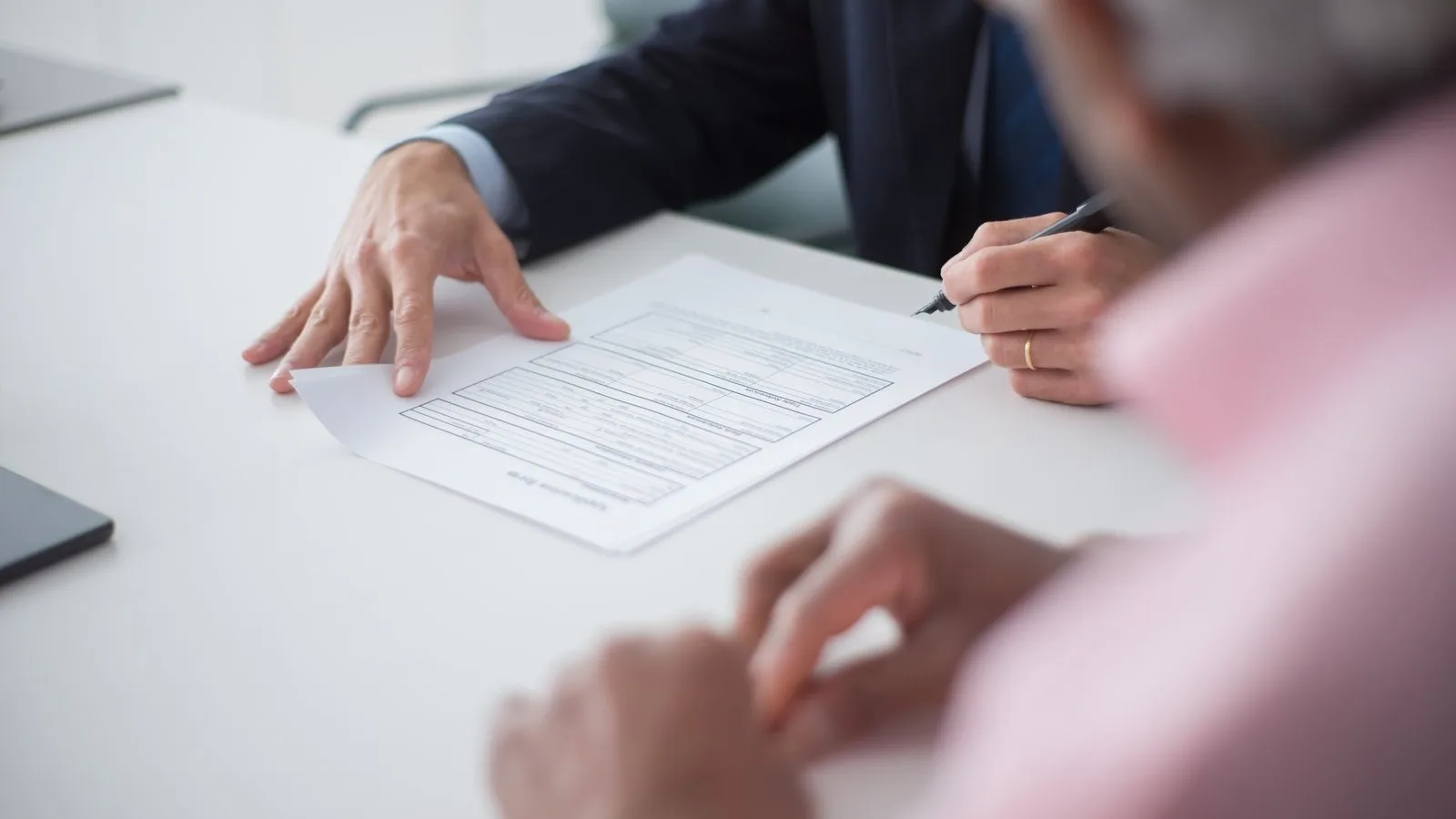 Two people going through the paperwork of a case file on an office desk