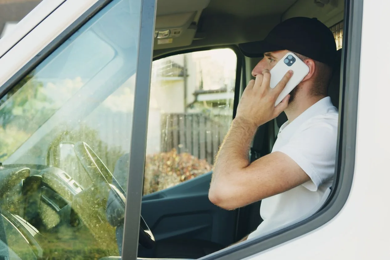 Un autònom amb gorra atén una trucada assegut a la furgoneta, el contacte que hauria de comptar com a conversió a Google Ads