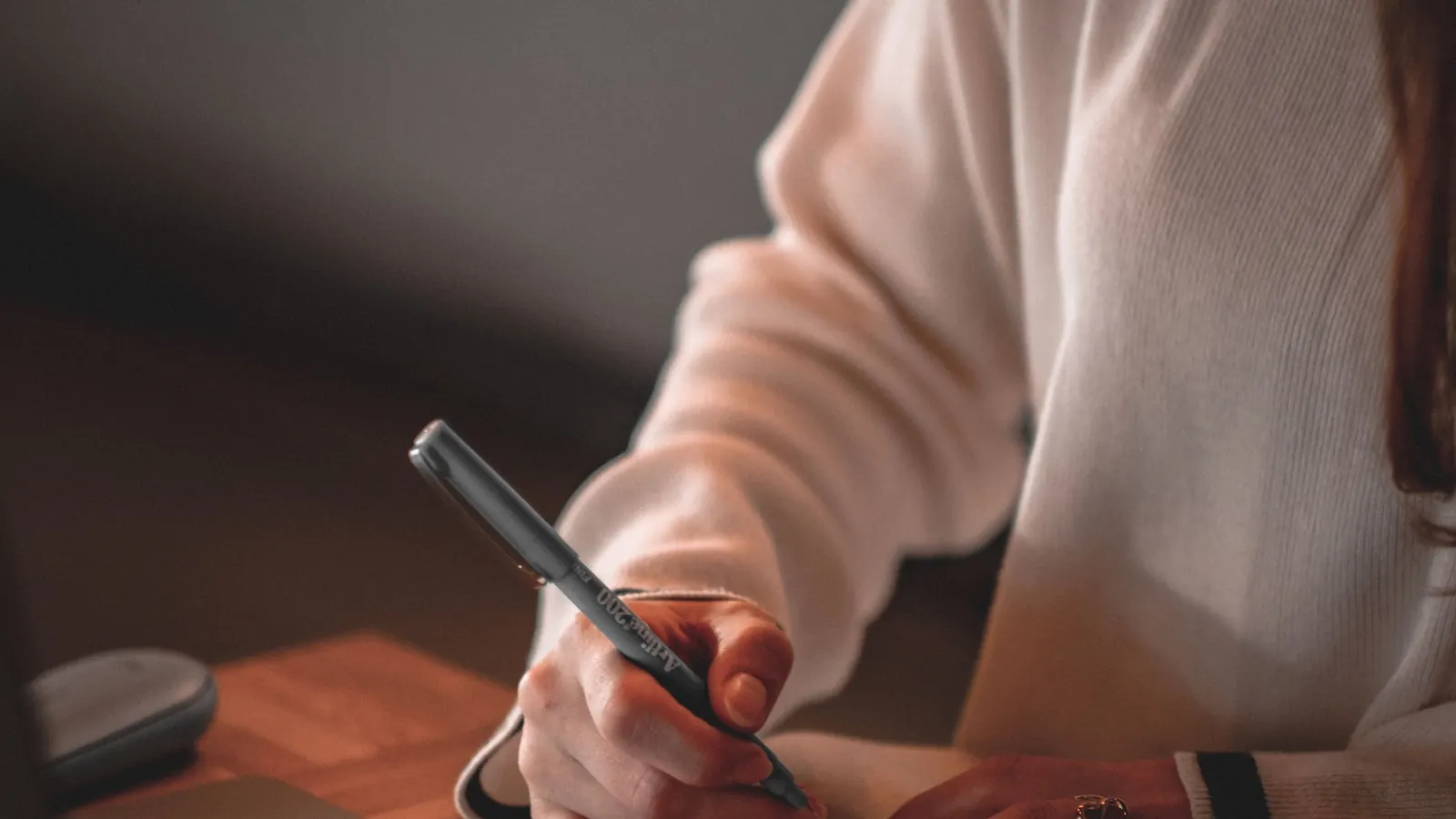 Persona escrivint un article per al web de la seva empresa amb una llibreta de notes al costat