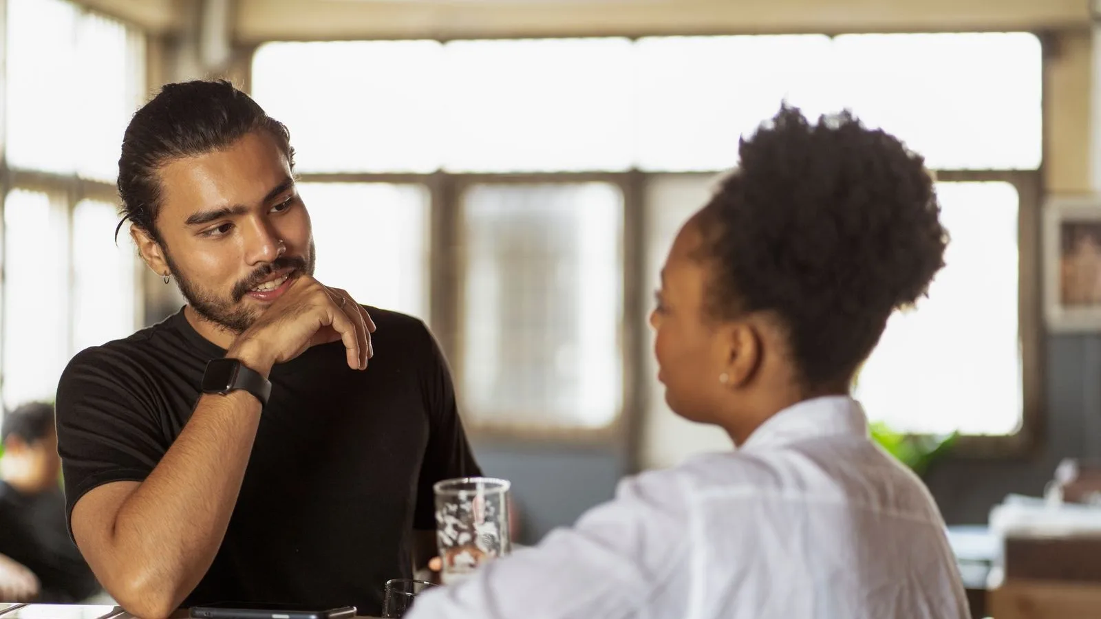 Dos personas hablando en la barra de un bar sobre una colaboración