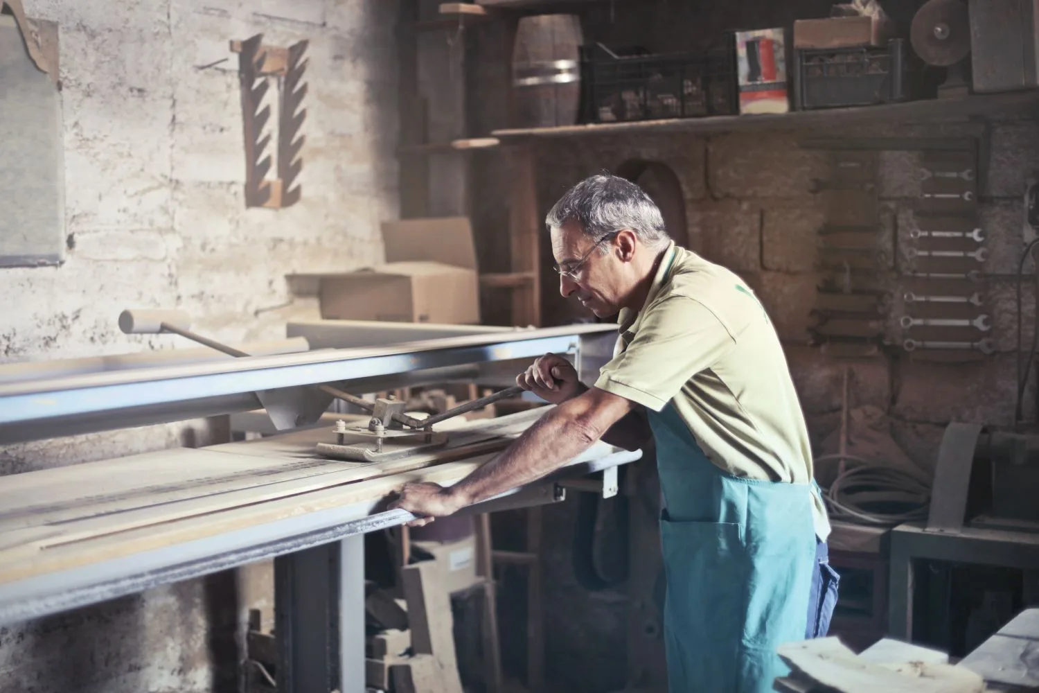 A carpenter in an apron working at the saw in his workshop, the hands-on experience a generic text can't give you
