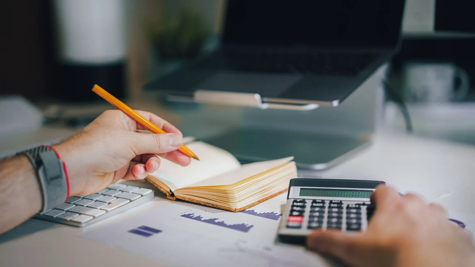 Propietària d'un negoci fent números amb la calculadora i el portàtil per decidir quant invertir en màrqueting digital
