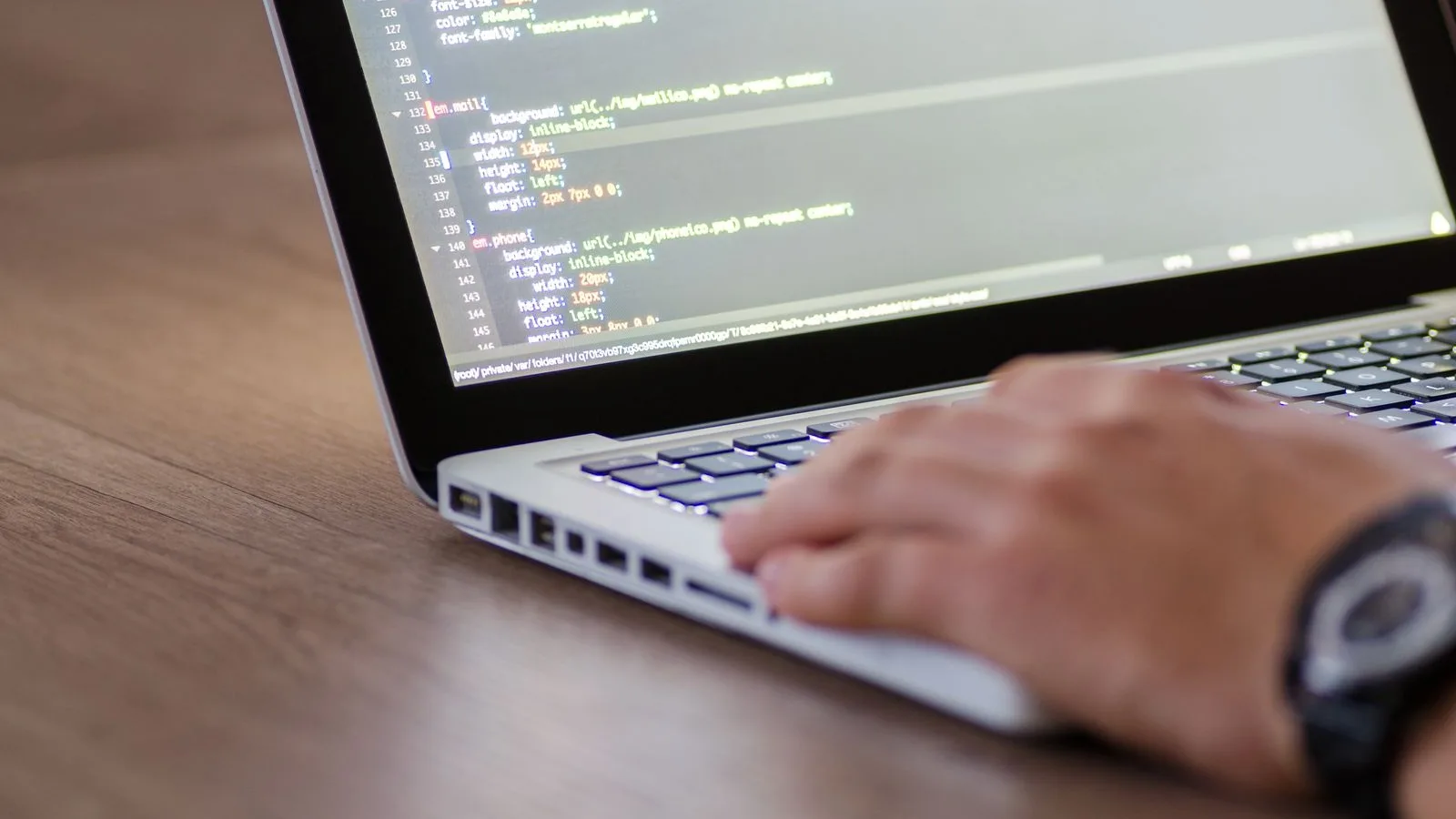Una mà tecleja en un portàtil amb el codi d'un web a la pantalla, el lloc on van les dades estructurades