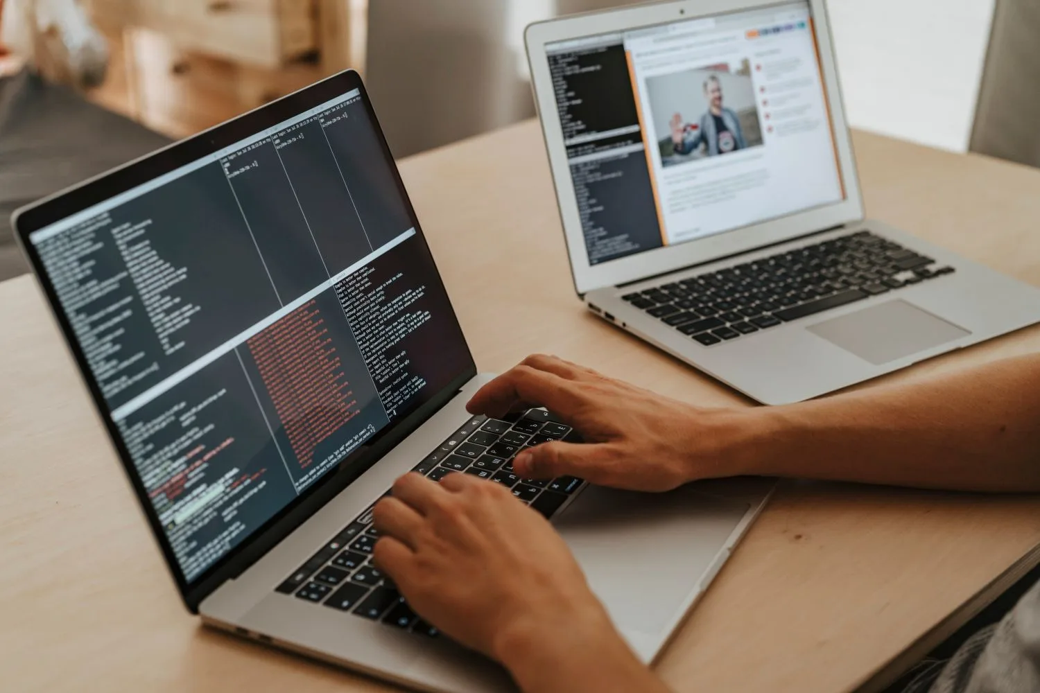 Hands coding a website on a laptop, with a second screen showing the finished site