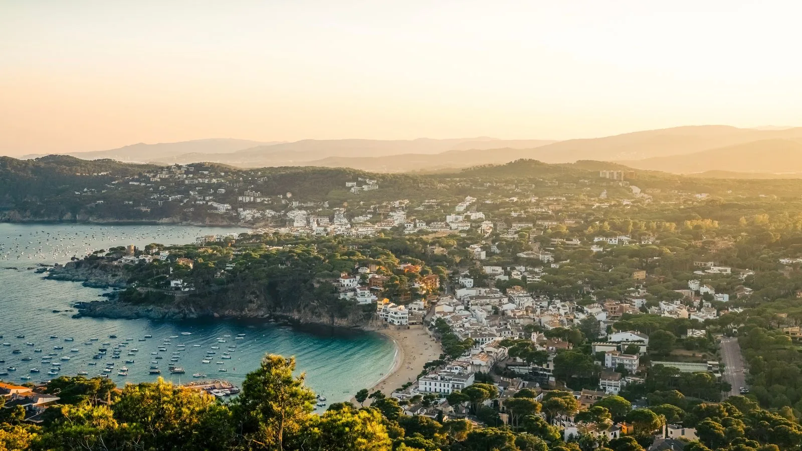 Cala de la Costa Brava amb cases blanques i barques al capvespre, el paisatge pel qual et busquen a Palafrugell