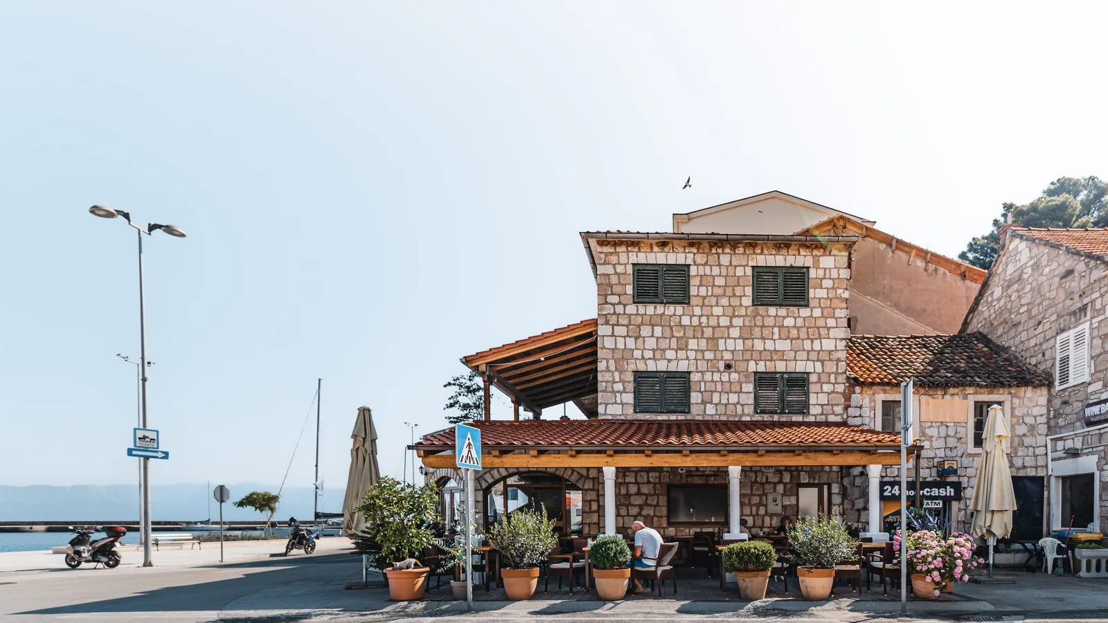 The seafront of a Costa Brava town with a stone restaurant and its terrace by the sea