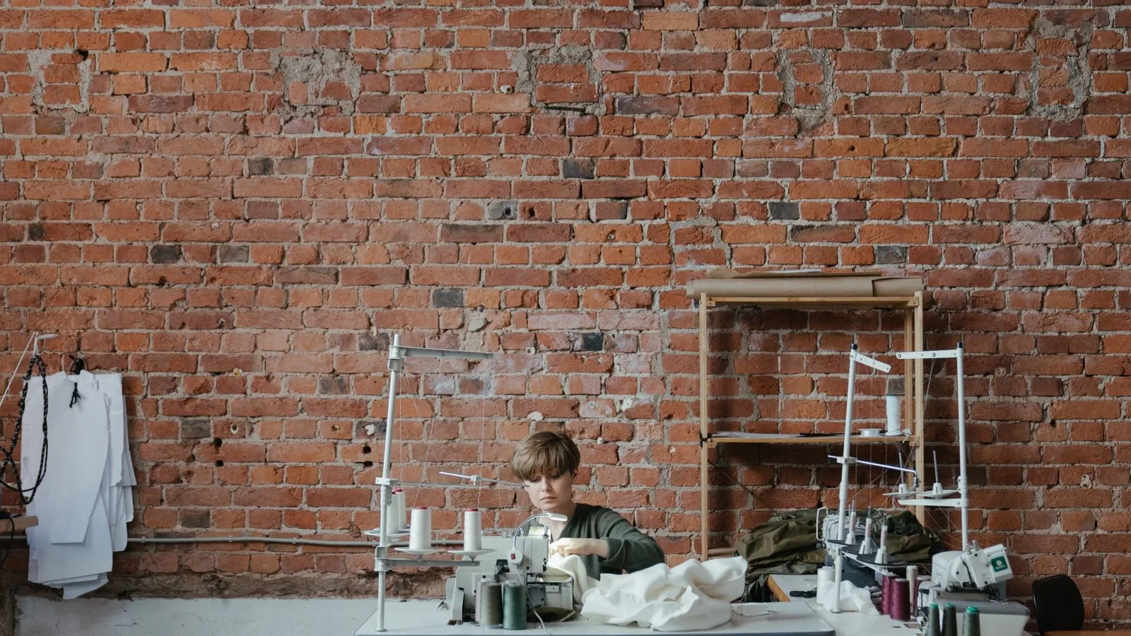 Someone working in a textile workshop with a brick wall, the kind of company that needs a clear website