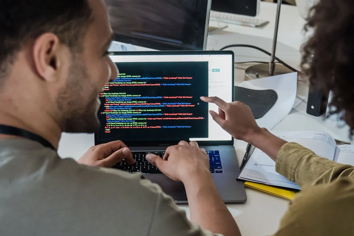 Equip de desenvolupament treballant davant de pantalles amb codi d'un programari a mida