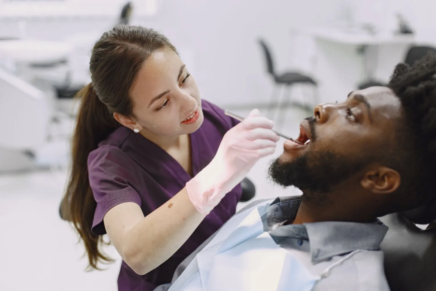 Una dentista amb guants revisa la boca d'un pacient a la consulta, el client que de debò paga una campanya d'anuncis