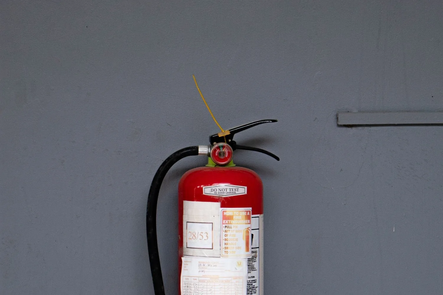 A fire extinguisher with its inspection label, a date that expires on its own