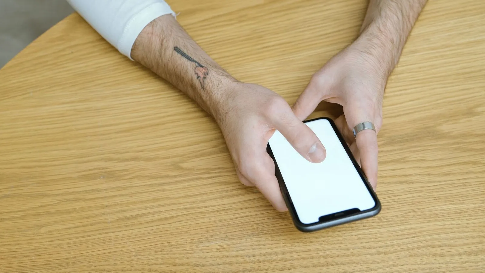 A thumb about to tap a phone screen on a wooden table, the gesture a call to action is after