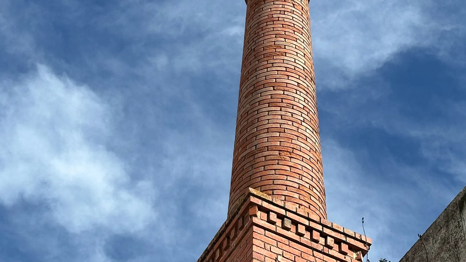 Chimenea de ladrillo de una antigua fábrica recortada contra el cielo, la estampa de las ciudades industriales del Vallès como Sabadell