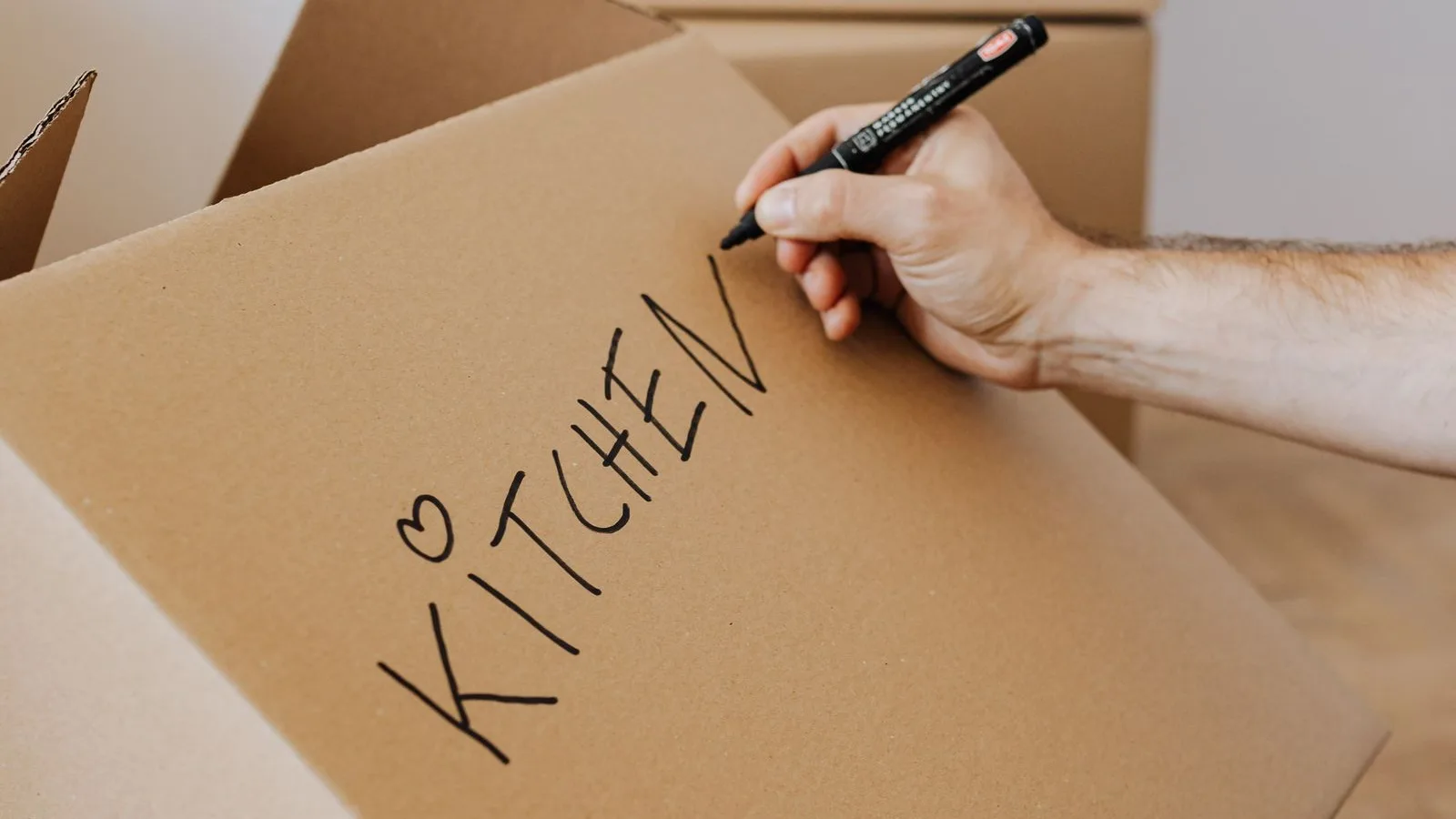 Mano etiquetando una caja de mudanza, el mismo cuidado con las etiquetas que pide migrar una web