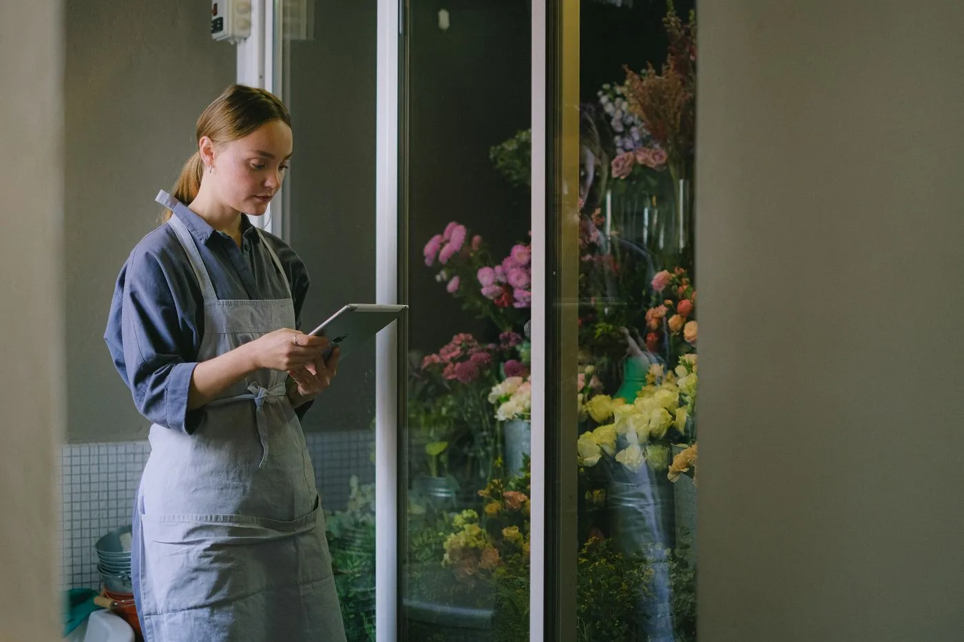 Florista consultant una tauleta al costat de la nevera de flors de la seva botiga