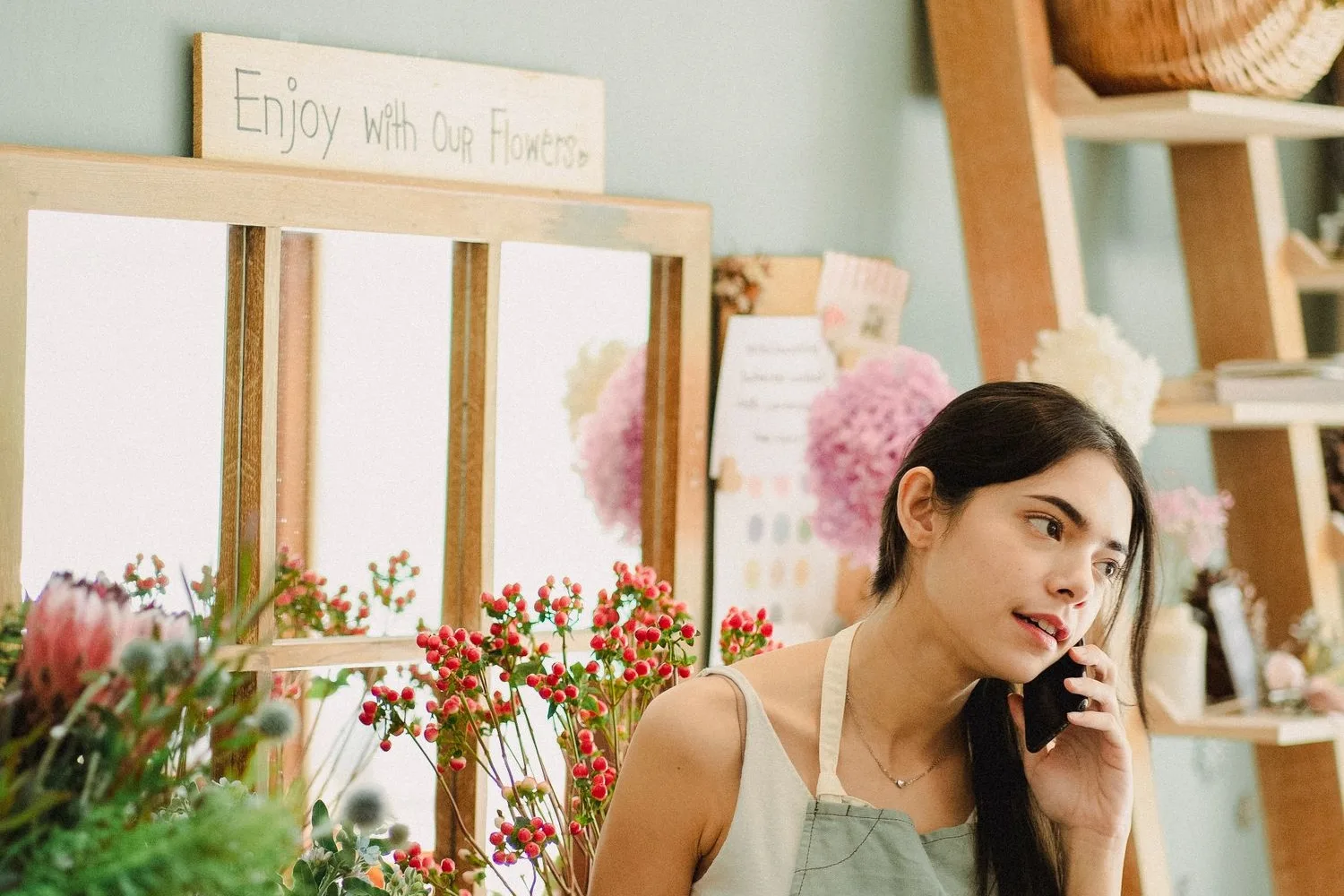 A shop owner taking a call in her store, the call that comes from the Google listing