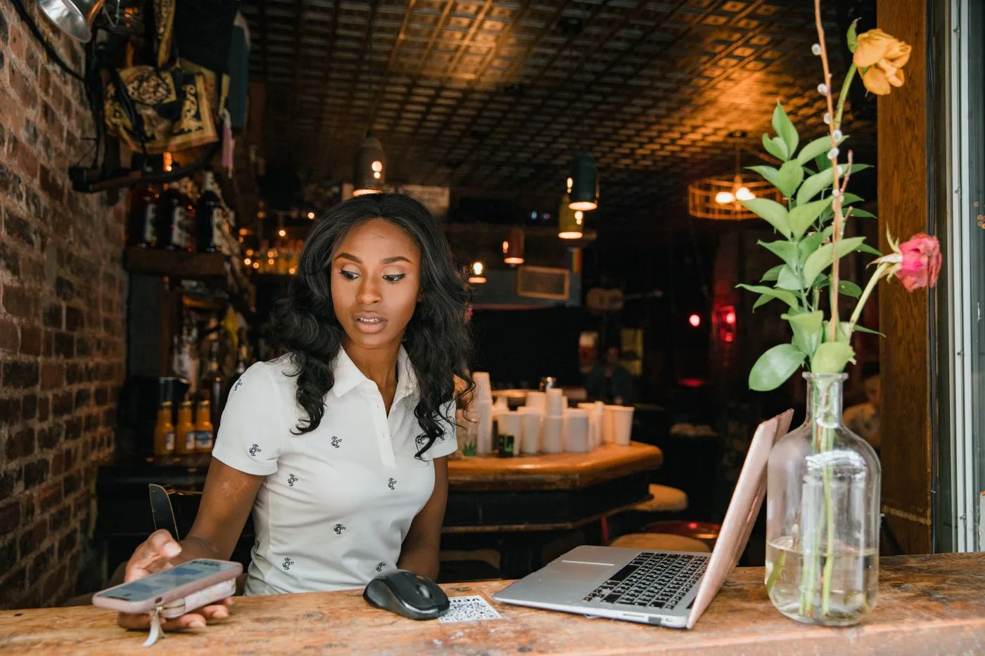 A business owner with a laptop and phone at the counter checking how her customers find her