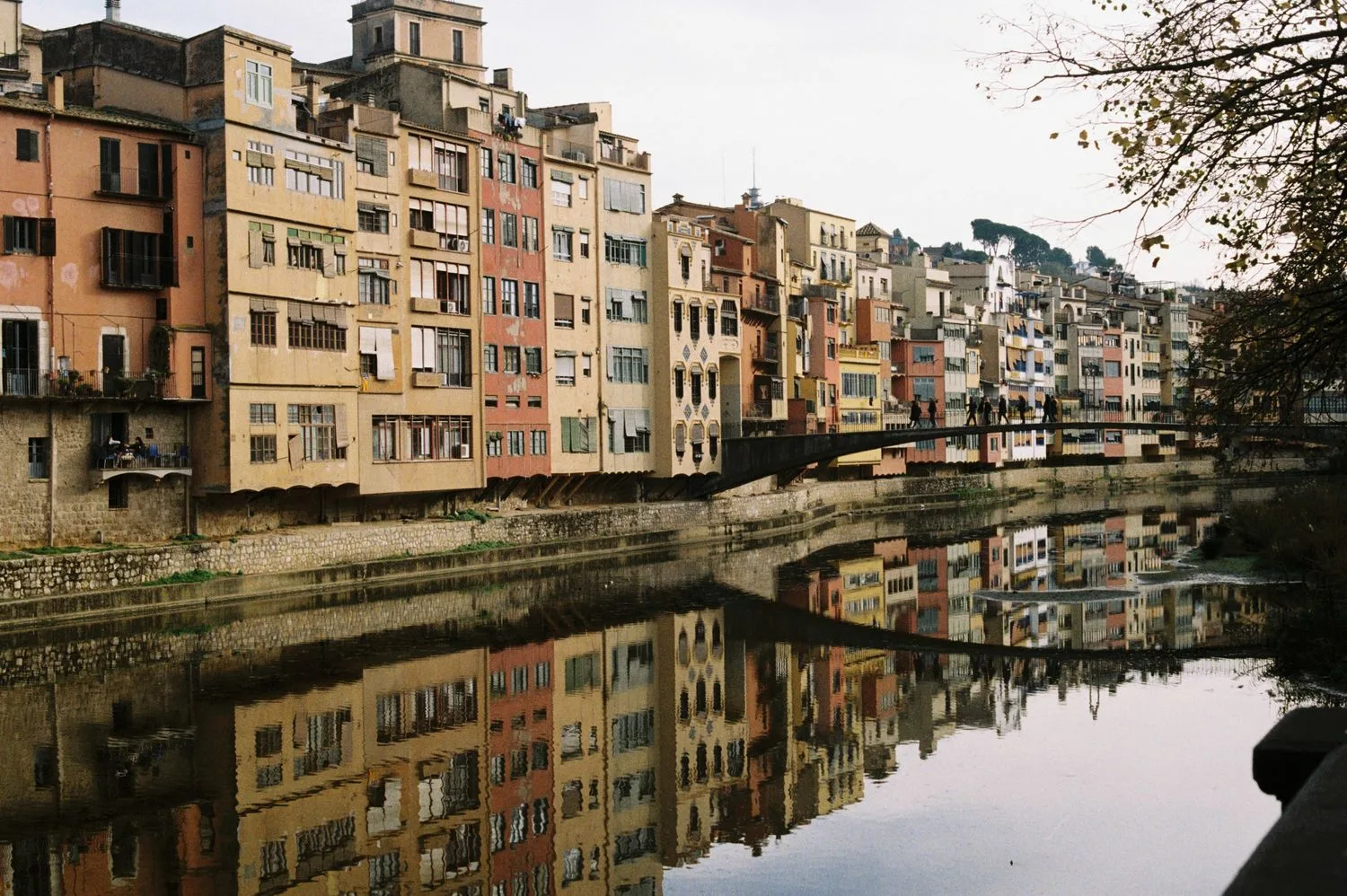 Façanes de colors reflectides al riu Onyar, amb els comerços de Girona que competeixen a les cerques locals