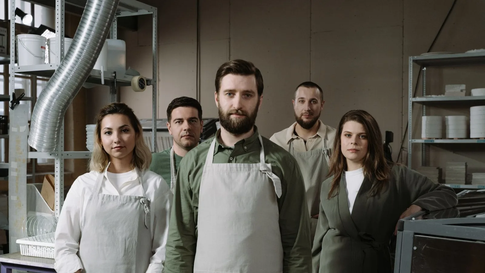 A small business team in aprons posing in their workshop, the people behind it