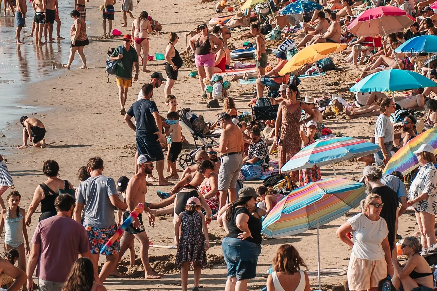 Platja mediterrània plena de gent, amb famílies, nens i para-sols en ple estiu, com les platges de Blanes en temporada alta