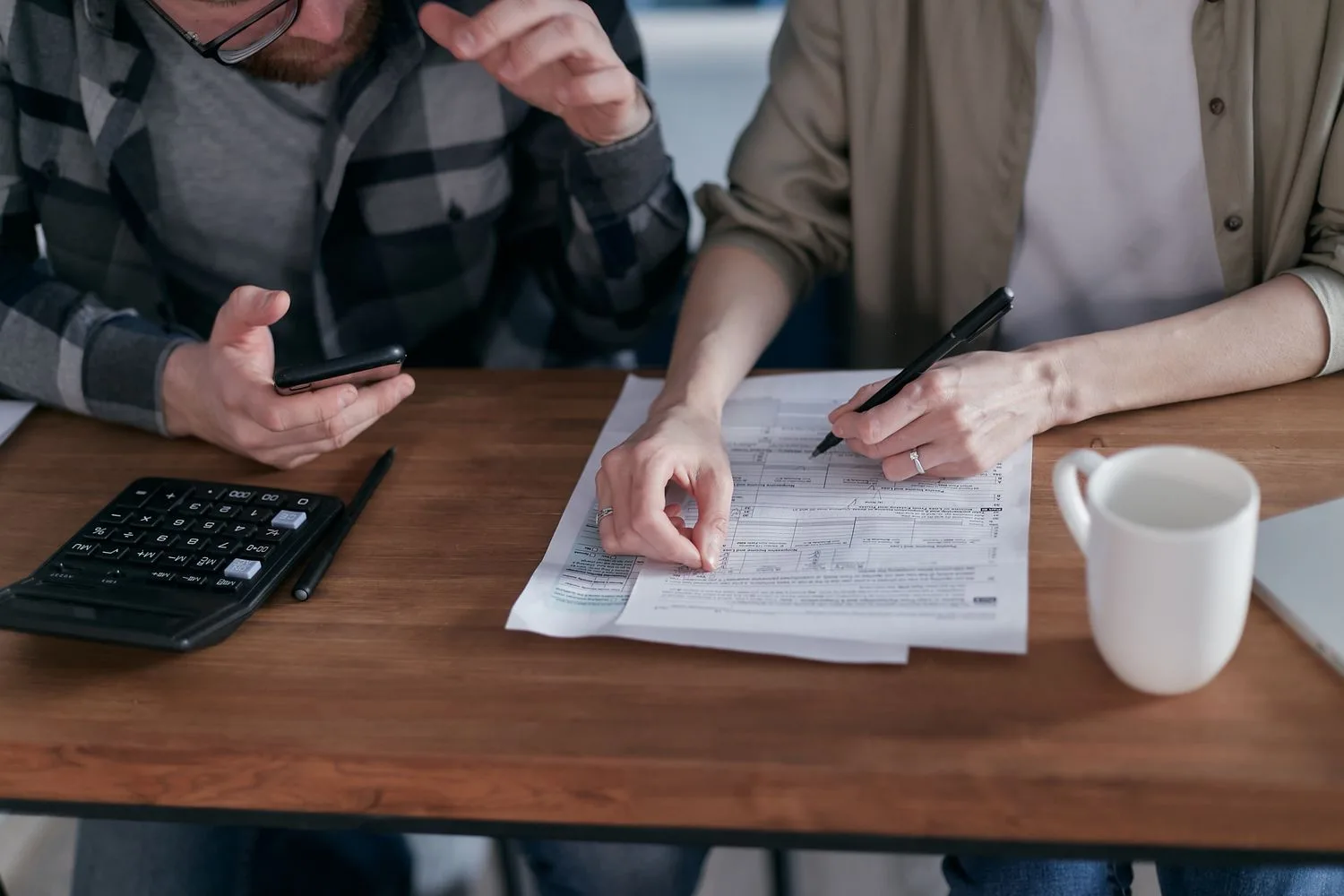 Dos personas revisan documentos del negocio con una calculadora y un móvil para preparar las pruebas de la apelación de la ficha de Google
