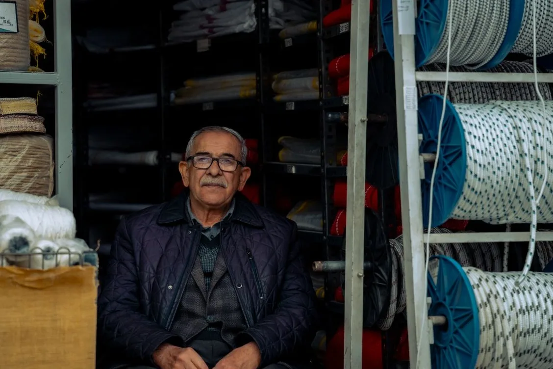 A veteran owner sitting in his hardware shop among the shelves, years of trade behind the business