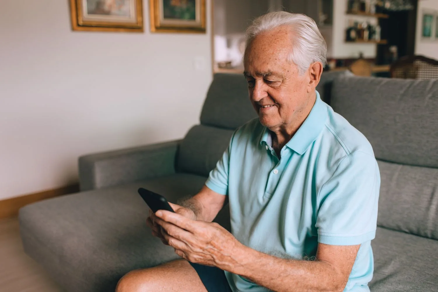 Client gran llegint un web al mòbil assegut al sofà de casa