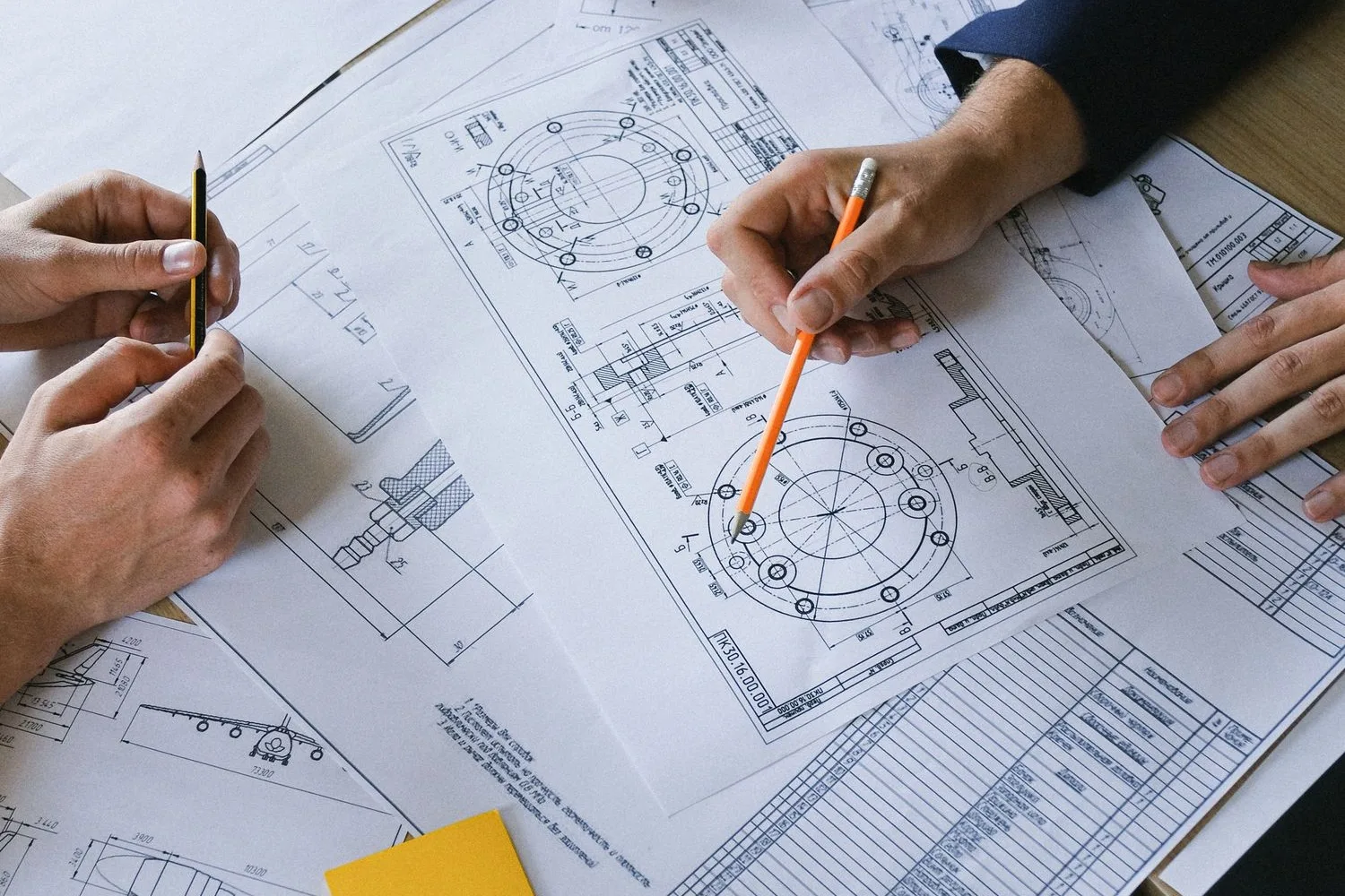 Hands going over technical drawings on a table before commissioning an industrial company website